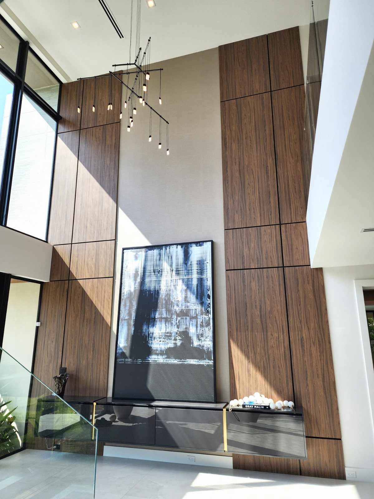 Wood grain wall panels mounted on a high ceiling in a modern living room.