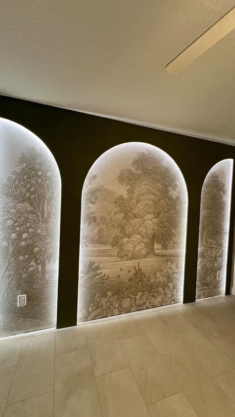 Three arched landscape wallpaper panels installed on a dark accent wall in a room.