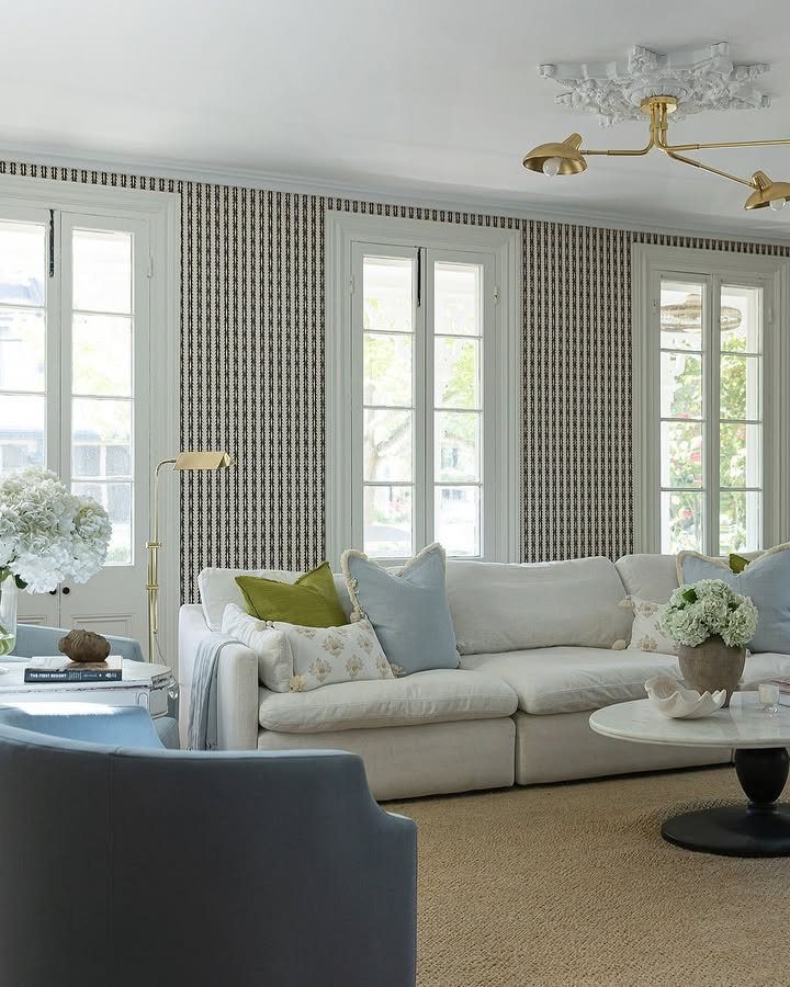 Patterned wallpaper accent wall in a bright living room with a white sofa and large windows.