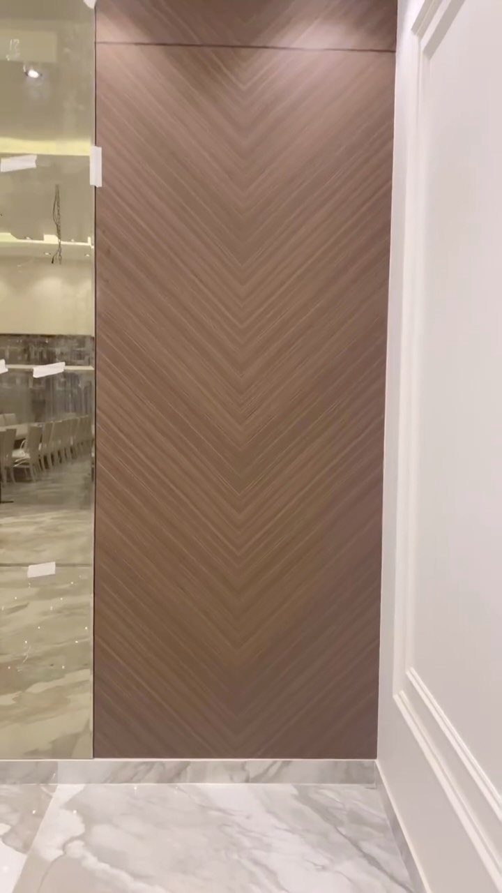 A light brown wood wall featuring a decorative chevron pattern design next to white walls.