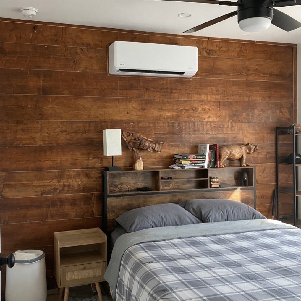 A bedroom with a dark horizontal wood plank accent wall and a bed with plaid bedding.