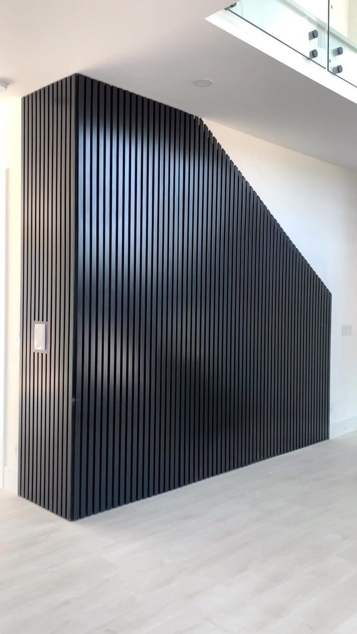 Black vertical wood slats covering a large interior wall with an angled ceiling line.