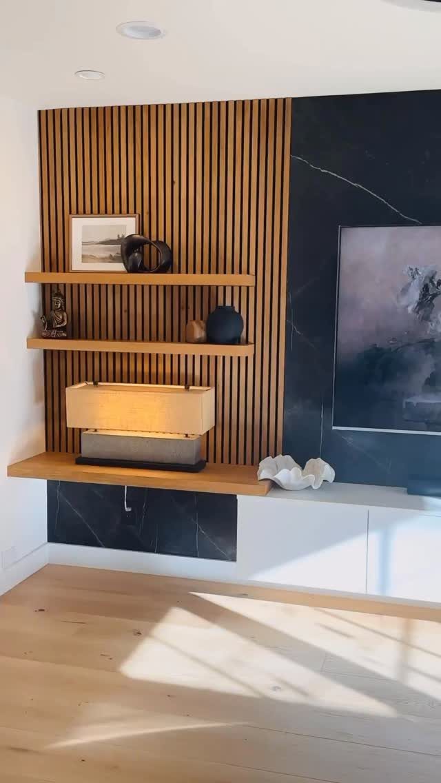Vertical wood slats on a wall with floating wooden shelves and dark marble paneling.