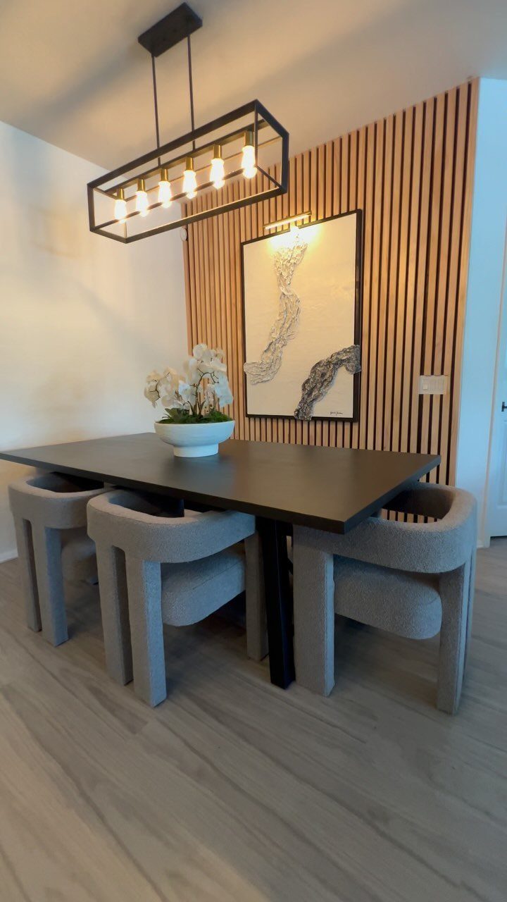 Dining table and grey chairs set against a vertical wood slat accent wall.