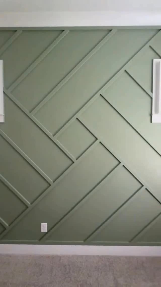 Sage green wall with a geometric pattern of raised wooden slats in diagonal lines.