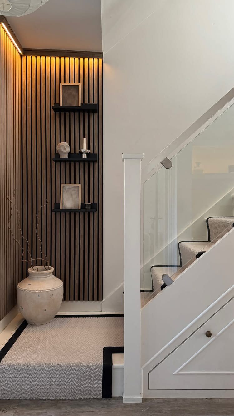 Vertical dark wood slats on an accent wall next to a white staircase and hallway.