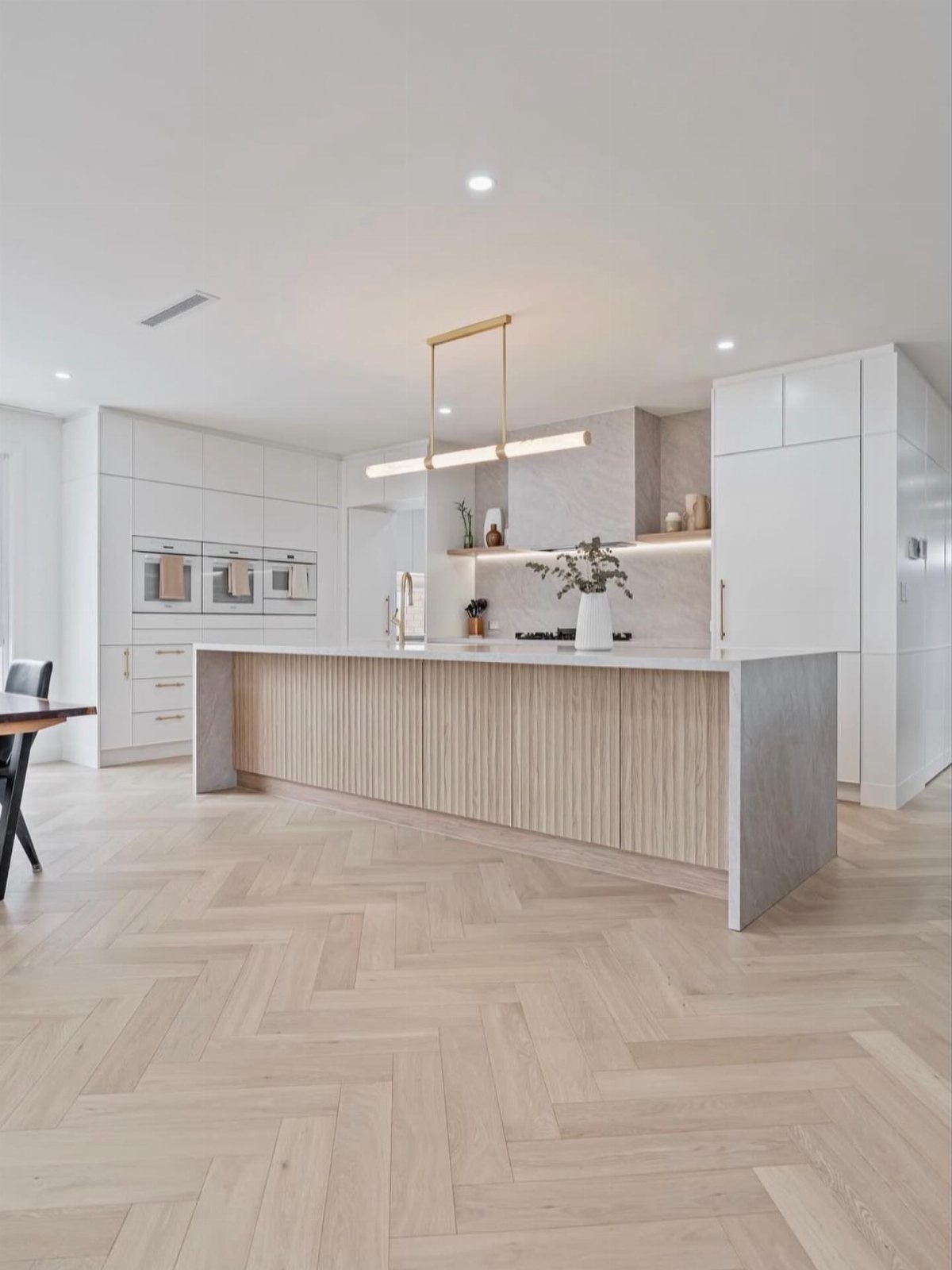 Wood Tile Pattern: 6 Layouts That Actually Work 1 Light wood floor tiles arranged in a herringbone pattern within a modern, bright kitchen.