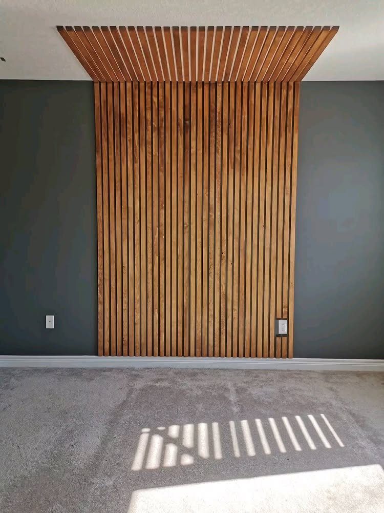 Wooden Plank Design: 6 Looks for Walls and Accents 6 Vertical wooden slats mounted on a dark grey wall extending to the ceiling.